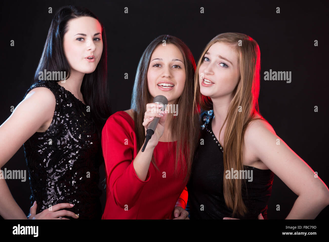 Group of three elegant beautiful young female singers singing with passion, musical trio Stock Photo