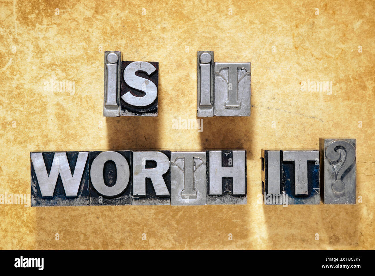 is it worth it question phrase made from metallic letterpress type on grunge cardboard background Stock Photo