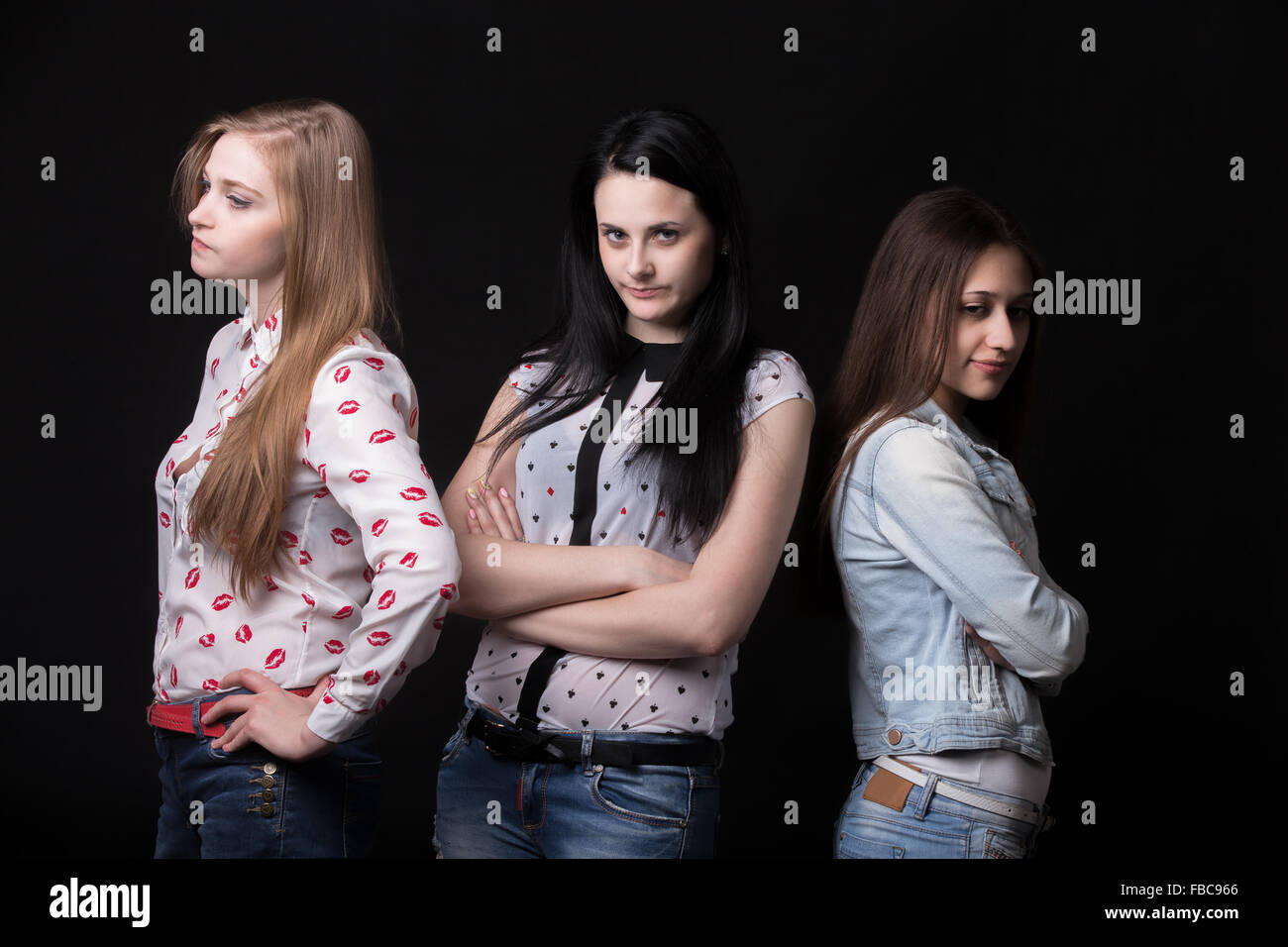Three teenage girlfriends looking away from each other, unhappy and angry because of disagreement or argument Stock Photo