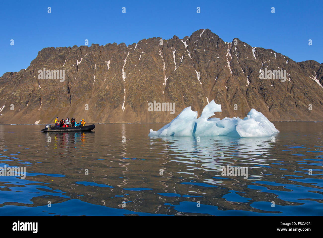 Eco-tourists in zodiac boat photographing melting iceberg in Lilliehöökfjorden, fjord in Krossfjorden, Spitsbergen, Svalbard Stock Photo