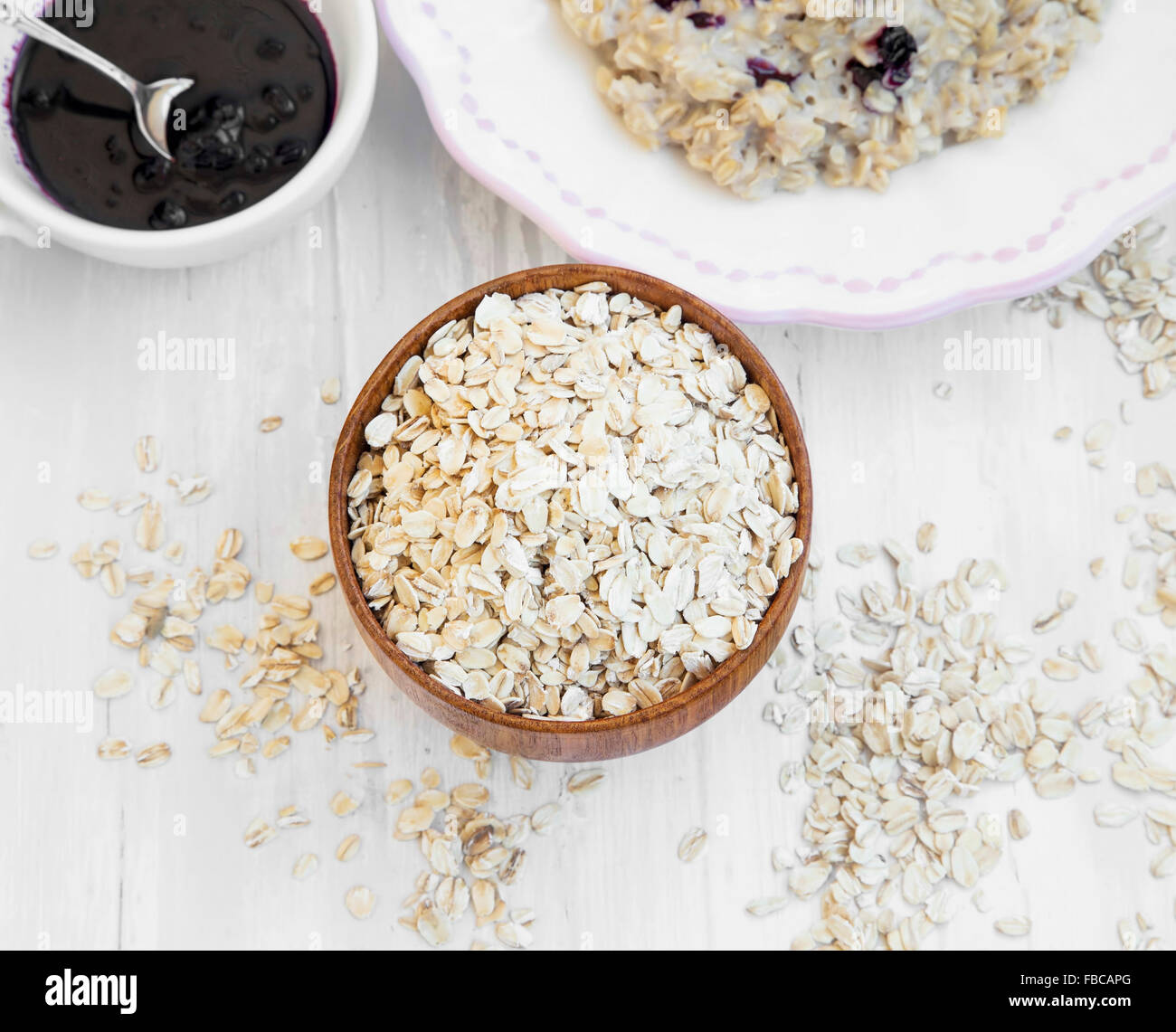 Oatmeal Cereals in a Wooden Bowl and Porridge in the Background Stock Photo