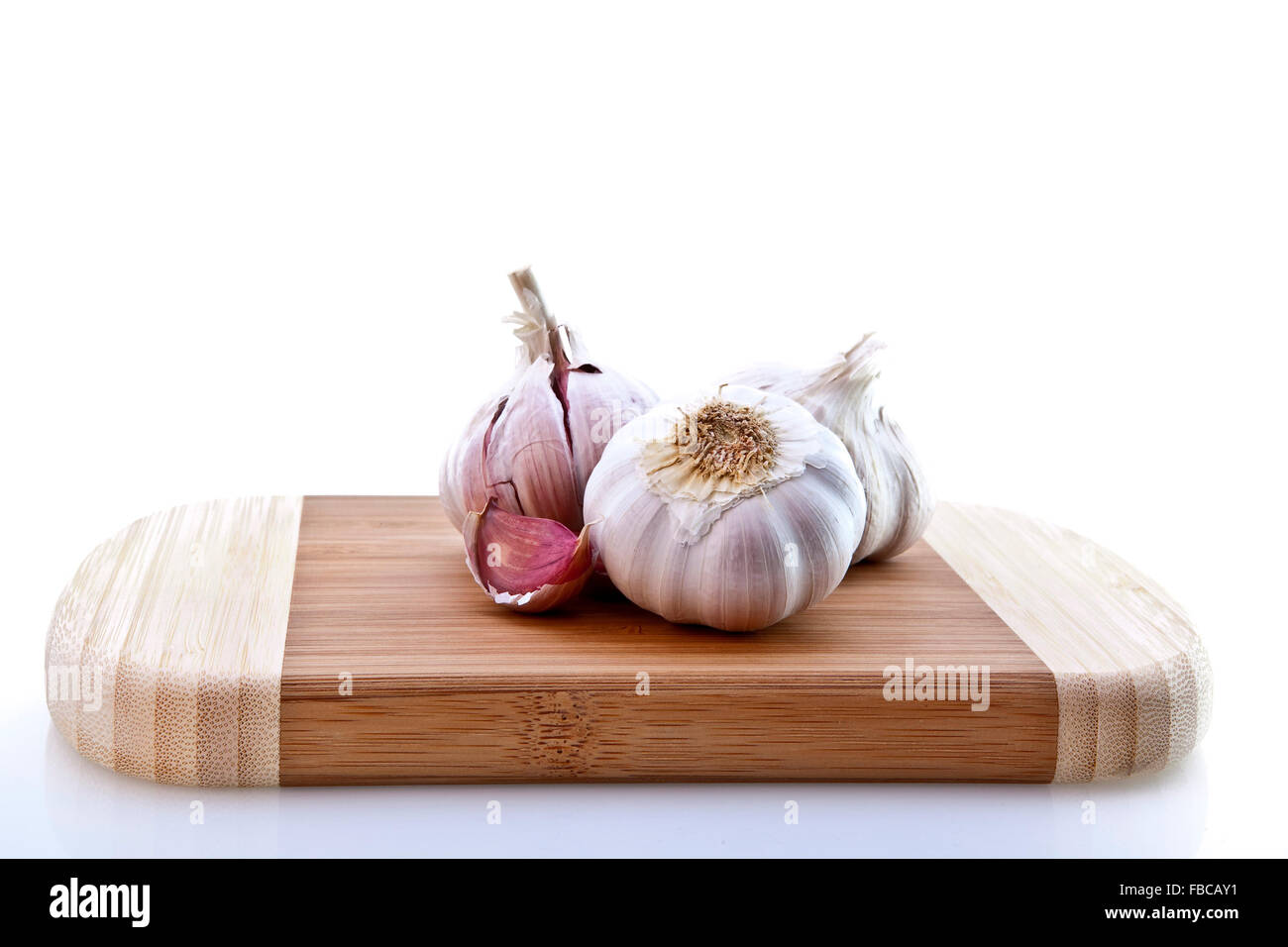 Cloves of garlic on wooden chopping board Stock Photo