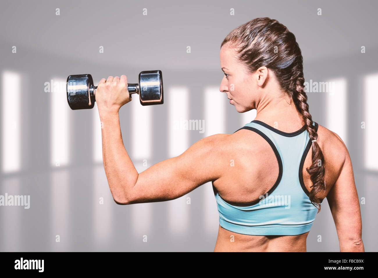 Composite image of rear view of woman lifting dumbbell Stock Photo