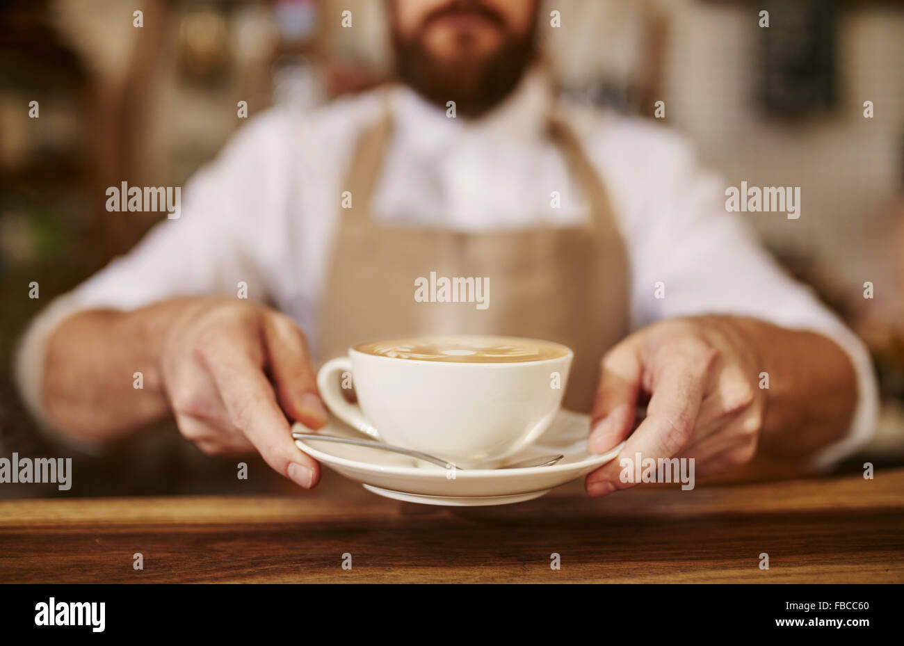 Close up of male barista serving cup of fresh coffee. Cup of coffee in the hands of waiter. Stock Photo