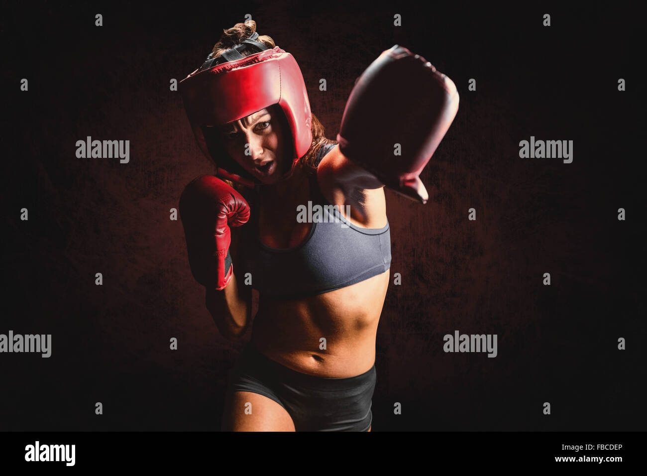 Composite image of female boxer with gloves and headgear punching Stock Photo