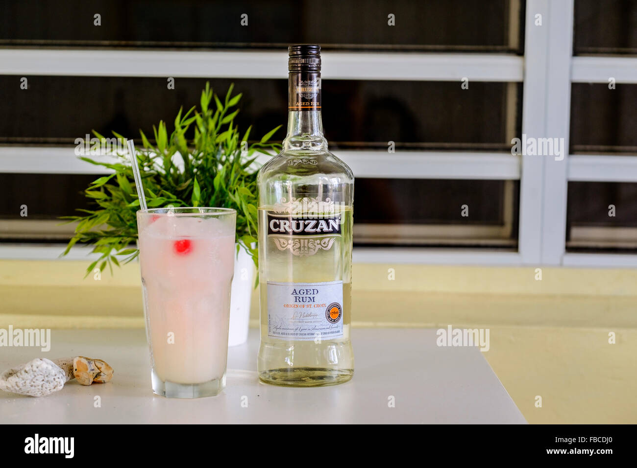 A bottle of Cruzan aged rum which is distilled on the island of St. Croix, VI, and a rum cocktail in a glass. Stock Photo