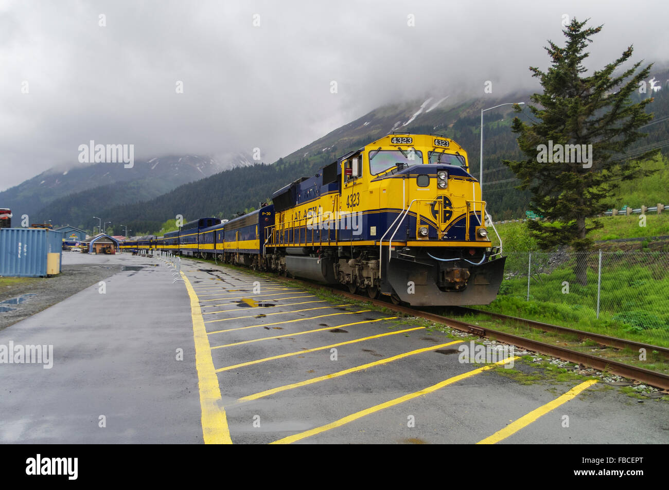 Alaska Railroad ARR diesel locomotive 4232, EMD SD70MAC, and passenger coaches in yellow and blue ARR livery. Seward, Alaska. Stock Photo