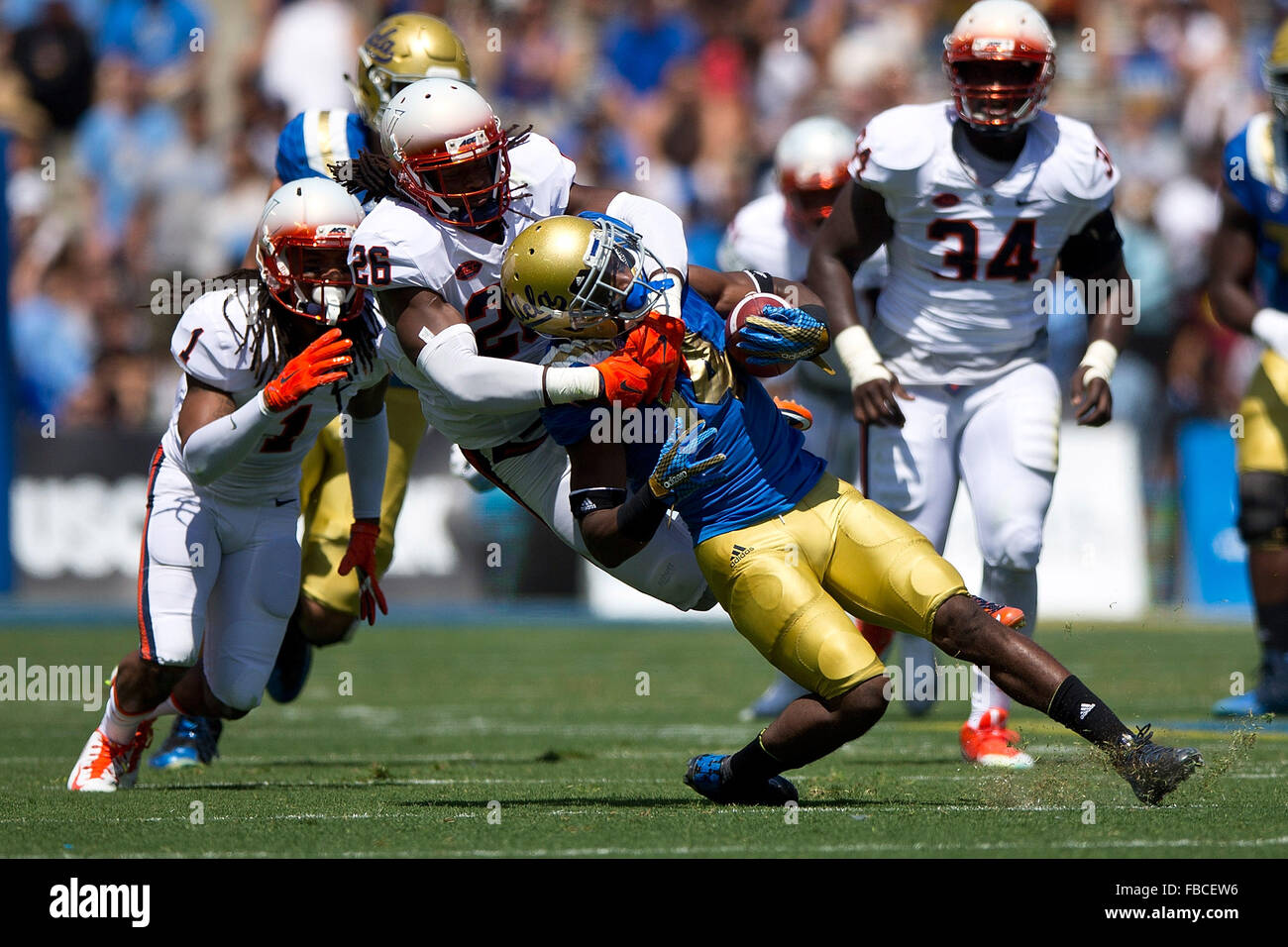 Wide receiver Mossi Johnson #14 of the UCLA Bruins is tacked by cornerback Maurice Canady #26 of the Virginia Cavaliers during Stock Photo