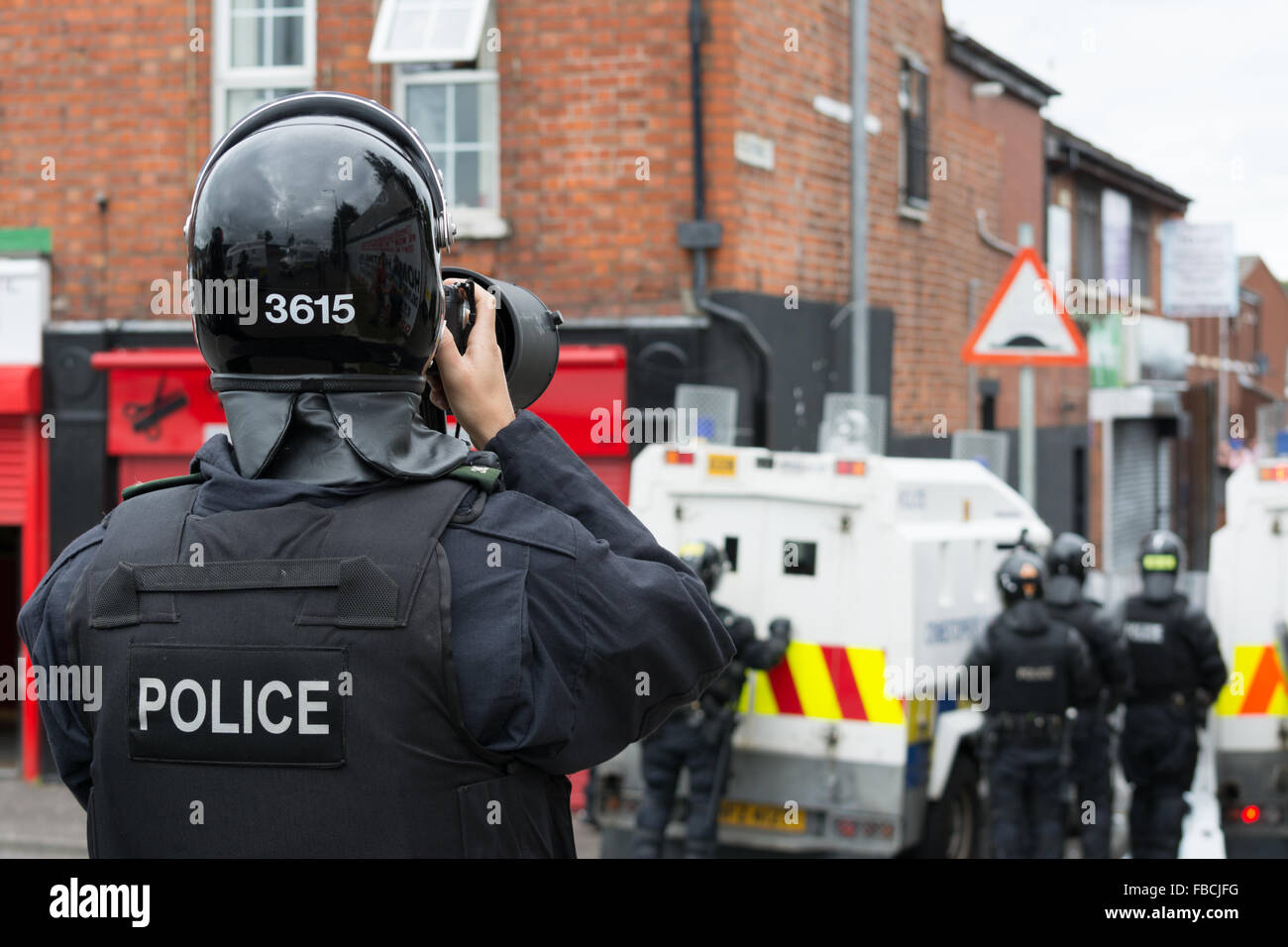 A PSNI police officer takes photographs for evidence during Irish Republican riot in North Belfast Stock Photo