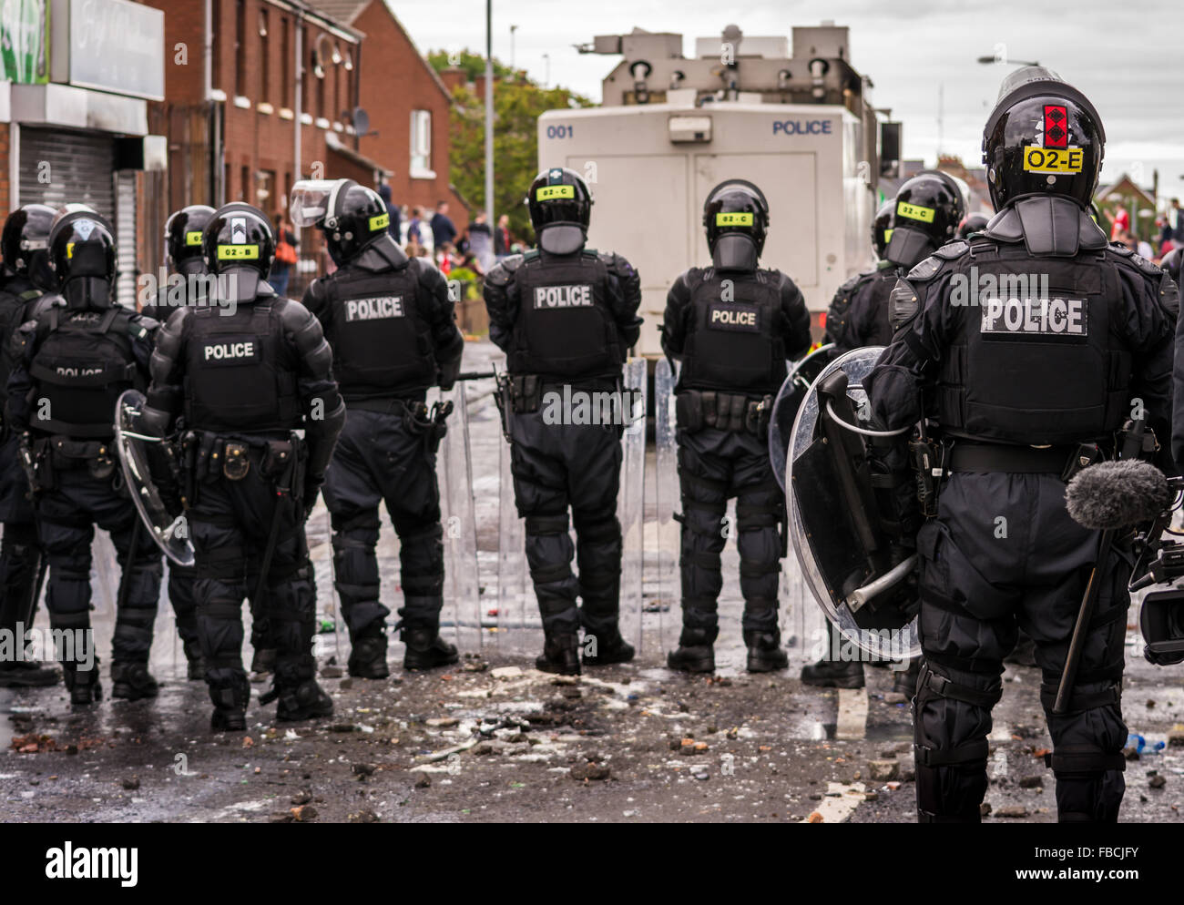 PSNI riot police officers line up behind a water cannon being used on Irish Republican rioters in Belfast Stock Photo