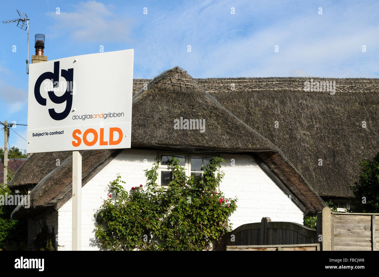 An estate agents sign outside a thatched cottage in Uffington, Oxfordshire, England, UK. Stock Photo