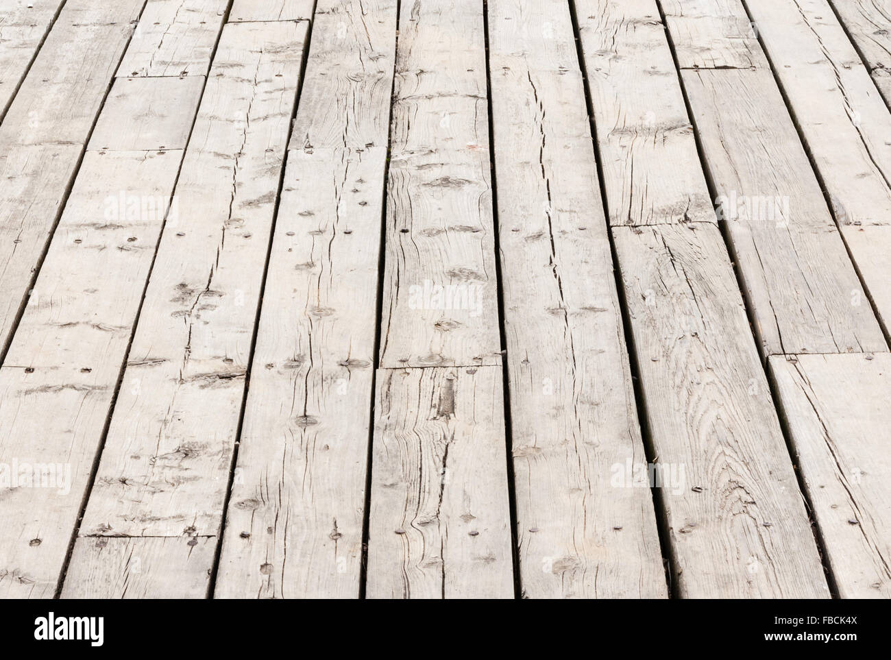 Cracked weathered gray wooden deck surface boards in perspective. Stock Photo