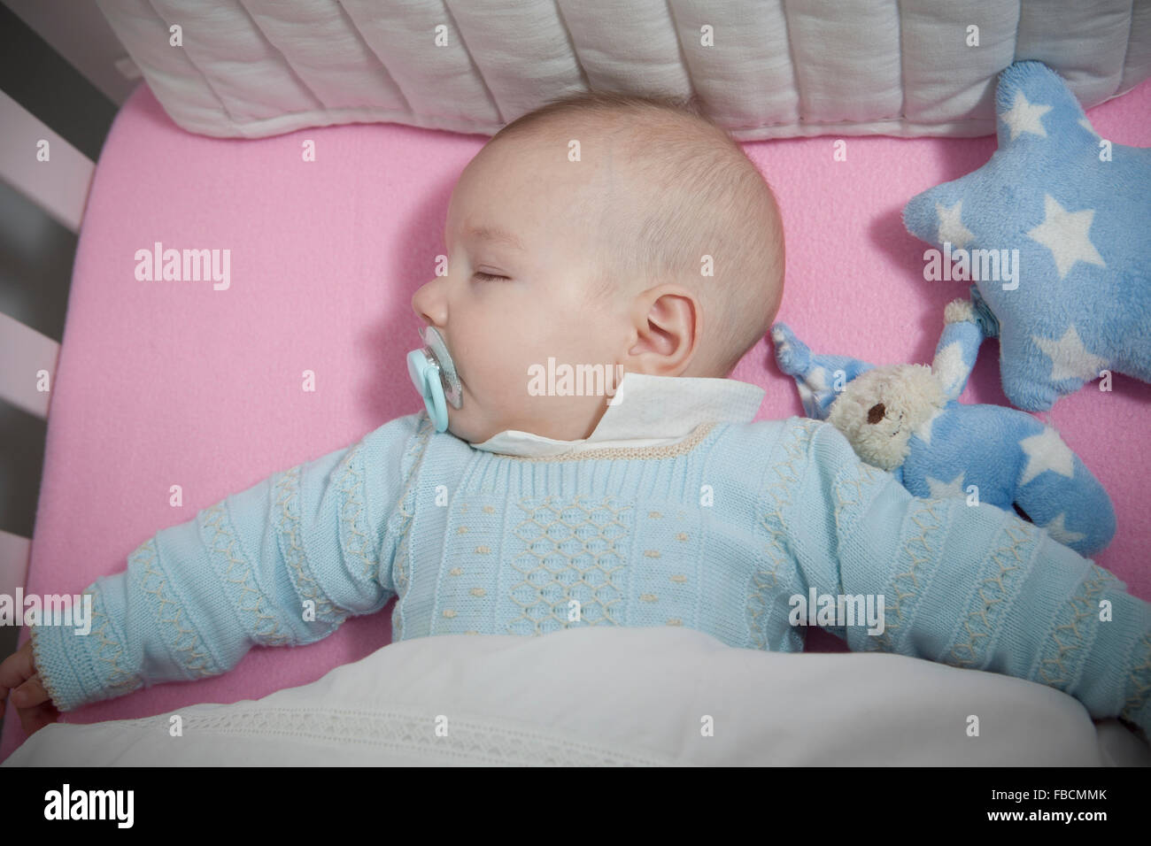 Sleeping four month baby boy lying in cot. Overhead view Stock Photo