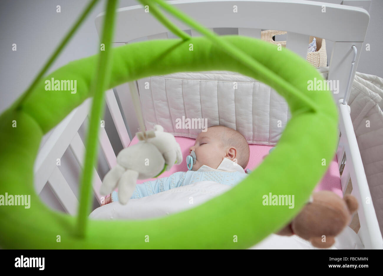 Sleeping four month baby boy lying in cot with mobile. Overhead view