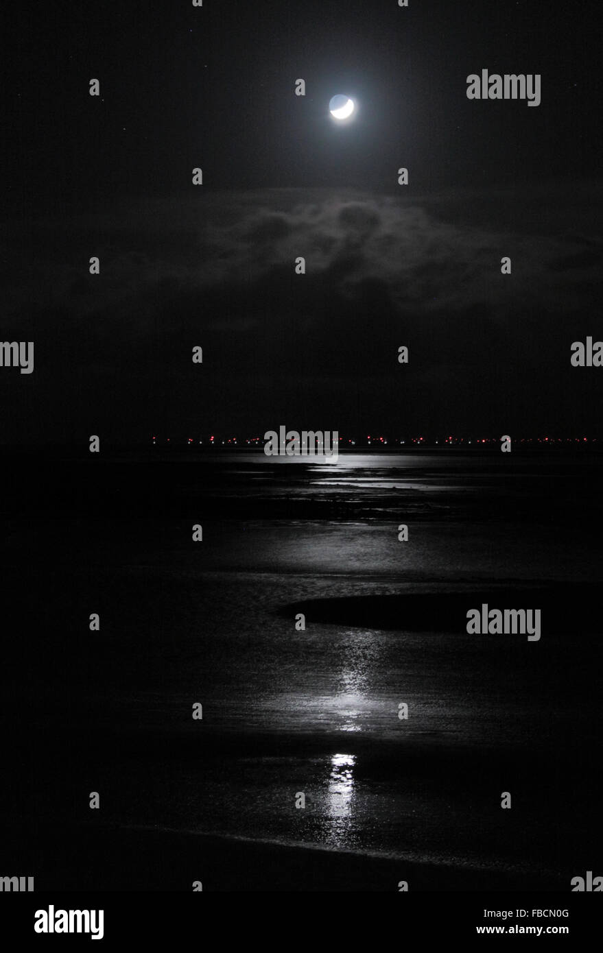 Morecambe Bay, Lancashire United Kingdom 14th January 2016,  The Moon reflects across the water and sand in Morecambe Bay , over the  lights of Duddin Sands Wind Farm Credit:  David Billinge/Alamy Live News Stock Photo