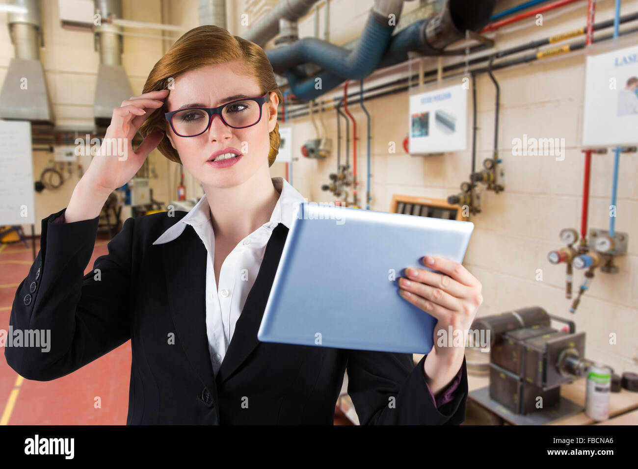 Composite image of redhead businesswoman using her tablet pc Stock Photo