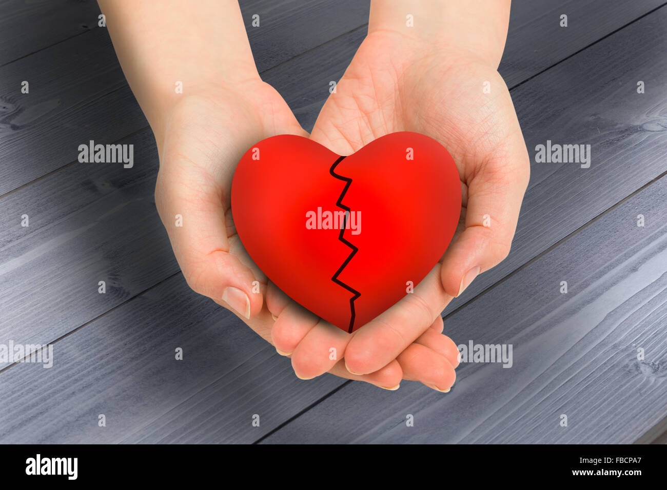 Composite image of couple holding broken heart in hands Stock Photo