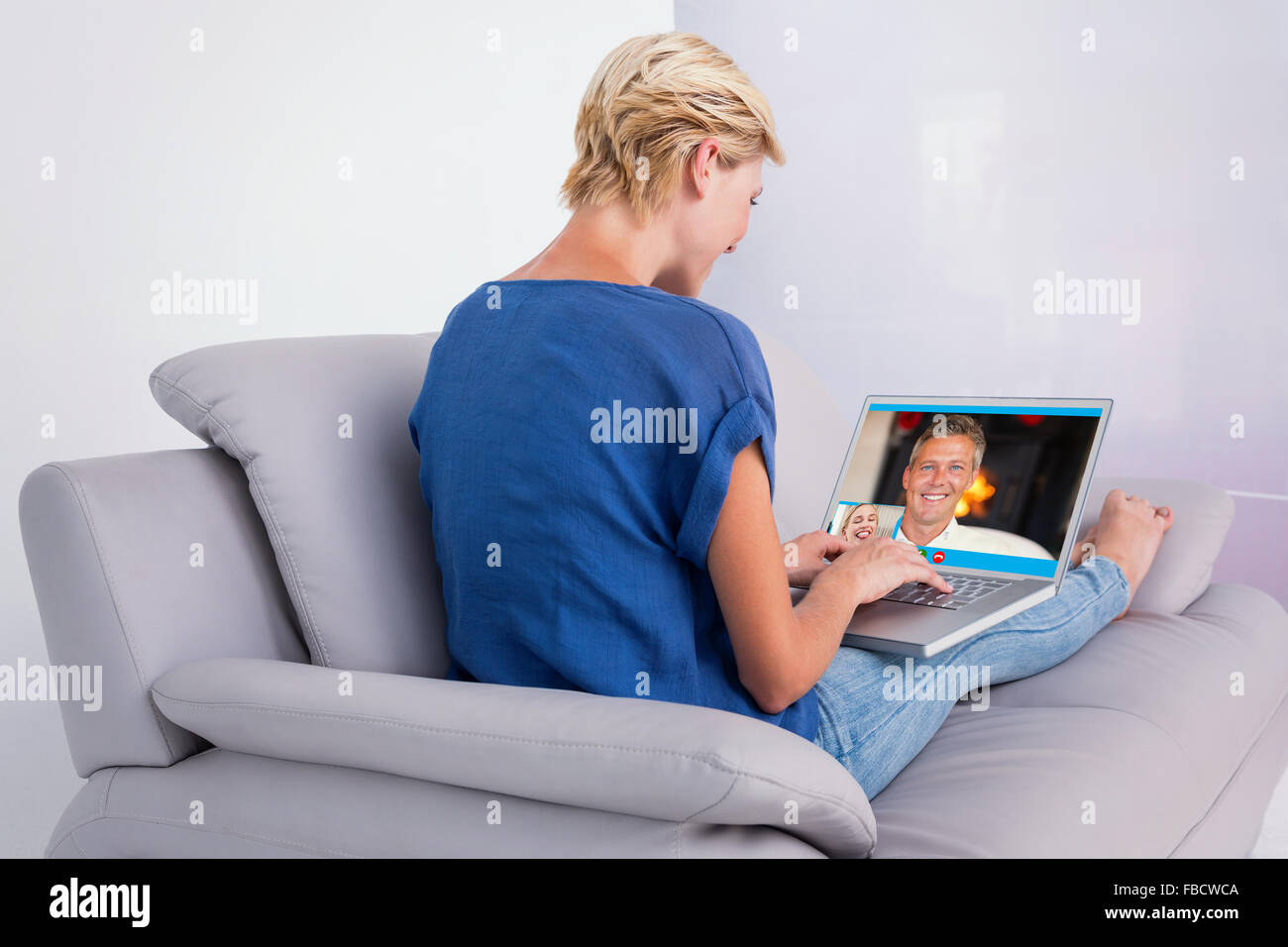 Composite image of blonde woman using her laptop on the couch Stock Photo