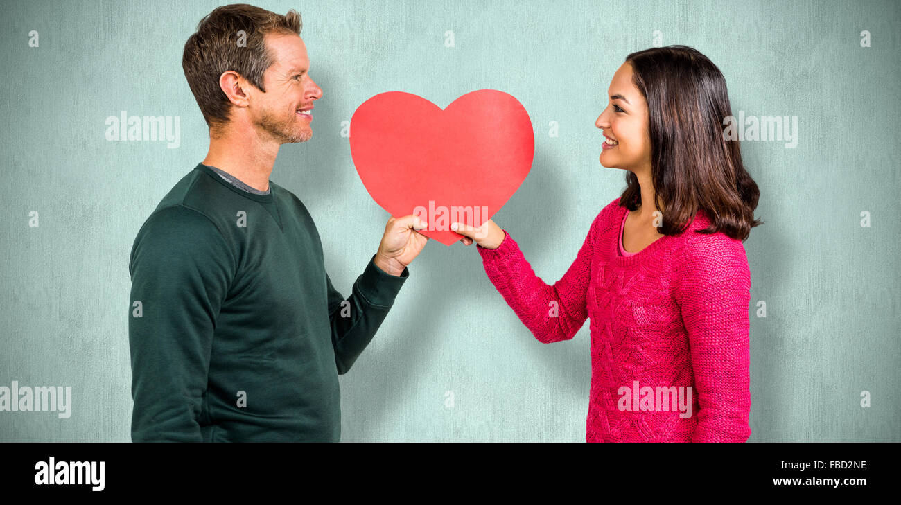 Composite image of smiling couple holding red heart shape Stock Photo ...