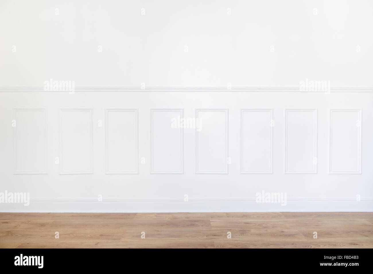 Empty white room with parquet floor and wood trimmed wall Stock Photo