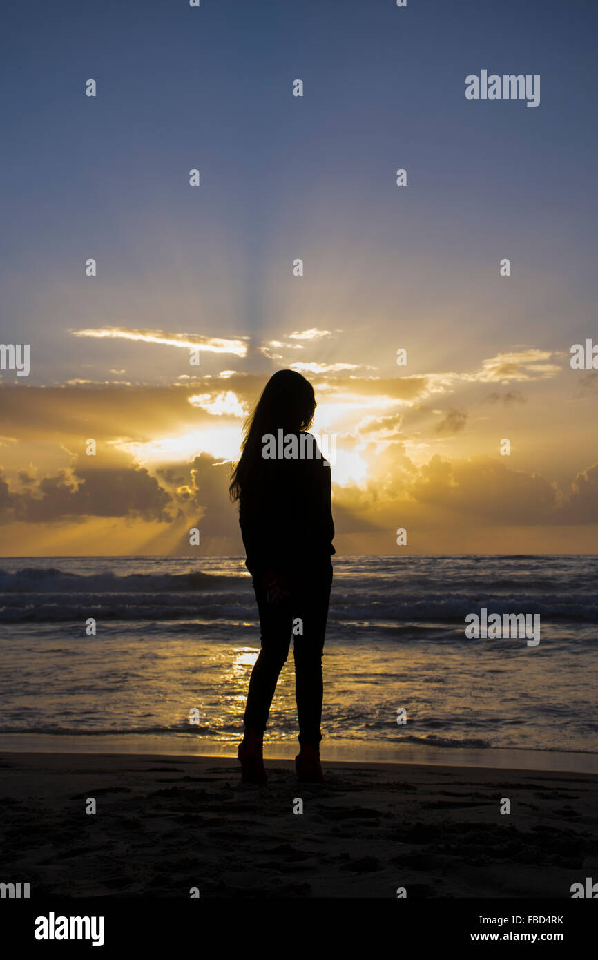 Silhouette of a woman standing on beach at sunset hi-res stock ...