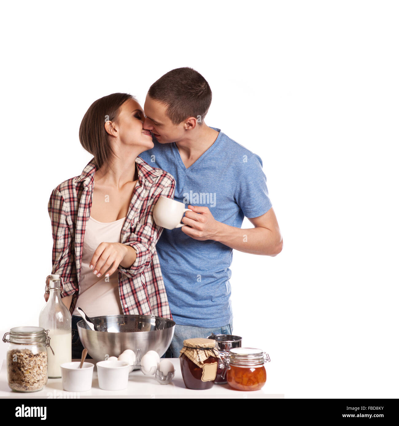 Affectionate man kissing his girlfriend while cutting bread for breakfast in the kitchen Stock Photo