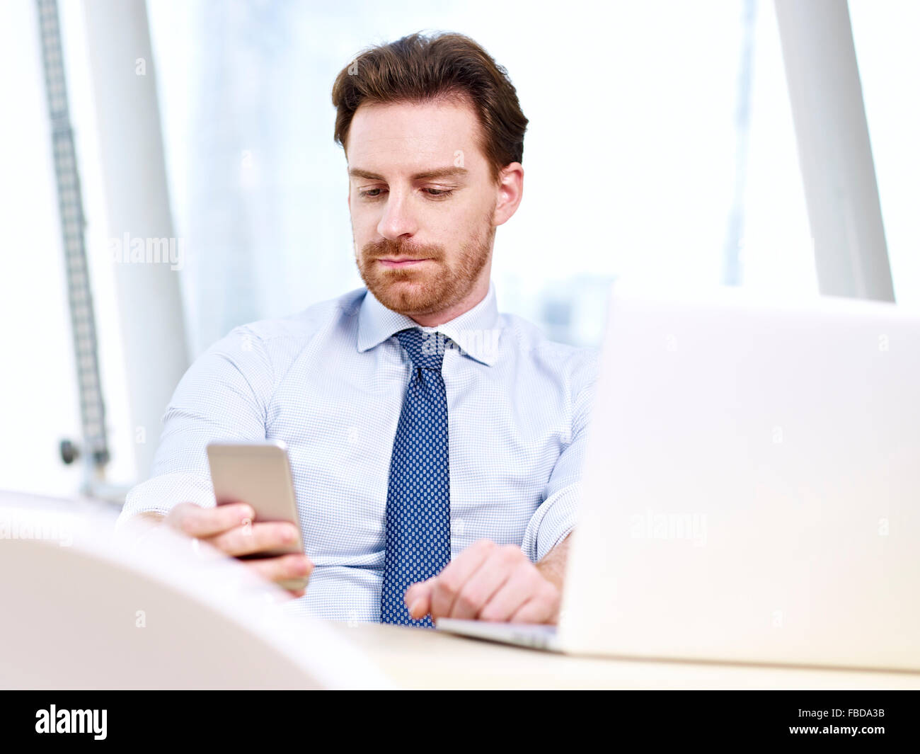 business person using cellphone and laptop in office Stock Photo