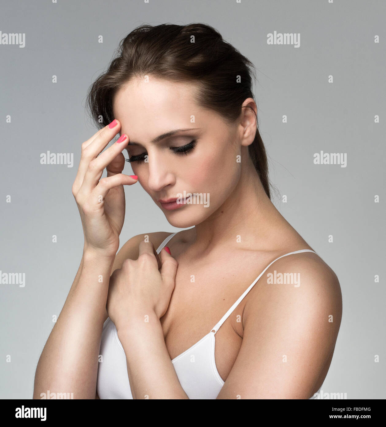 Beautiful woman touching head thinking headache. Pretty model, white strappy vest top Stock Photo