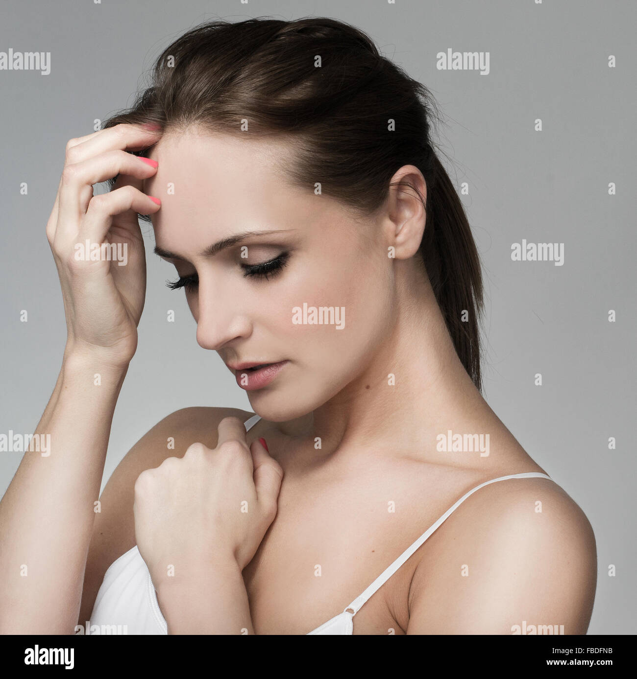 Beautiful woman touching head thinking headache. Pretty model, white strappy vest top Stock Photo