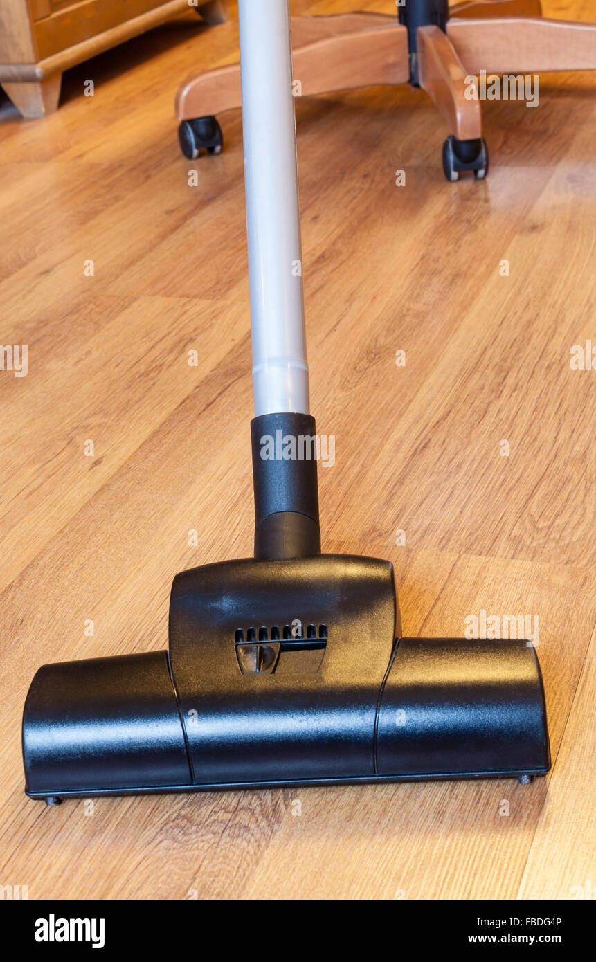 front view of vacuuming of parquet floor by vacuum cleaner at home Stock Photo