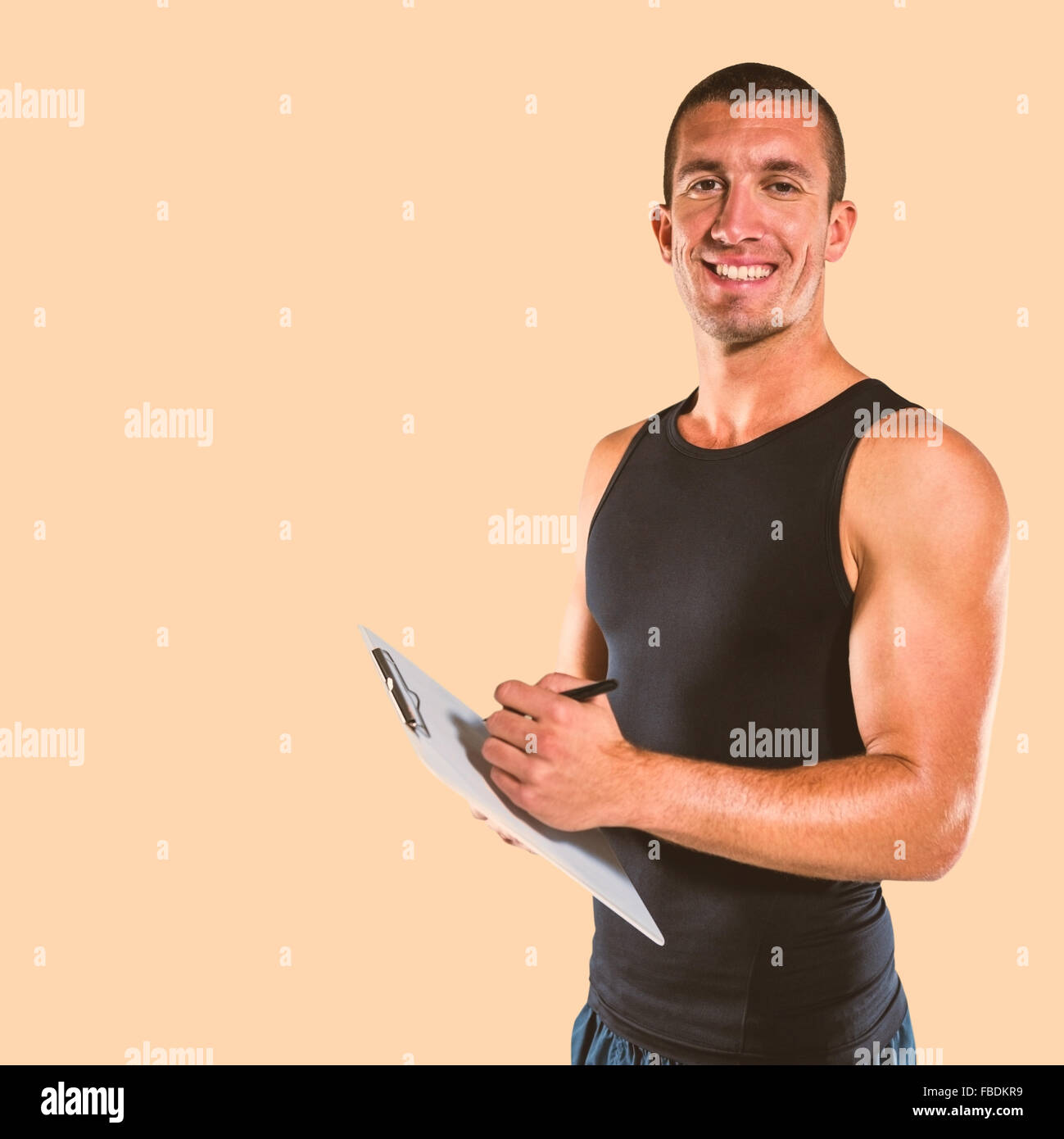 Composite image of smiling sports coach writing on clipboard Stock Photo