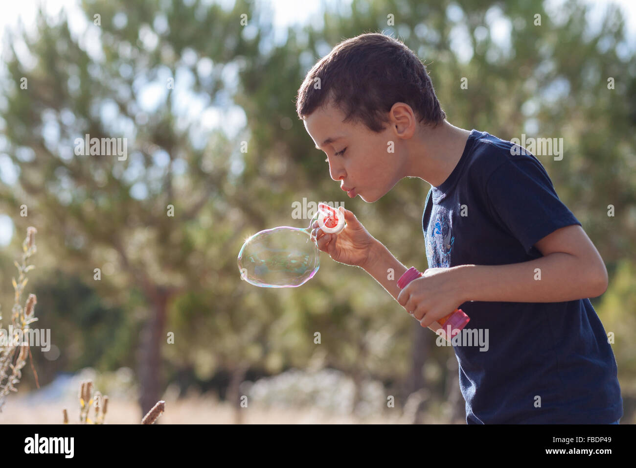 Boy Blowing Bubbles On Plants Stock Photo