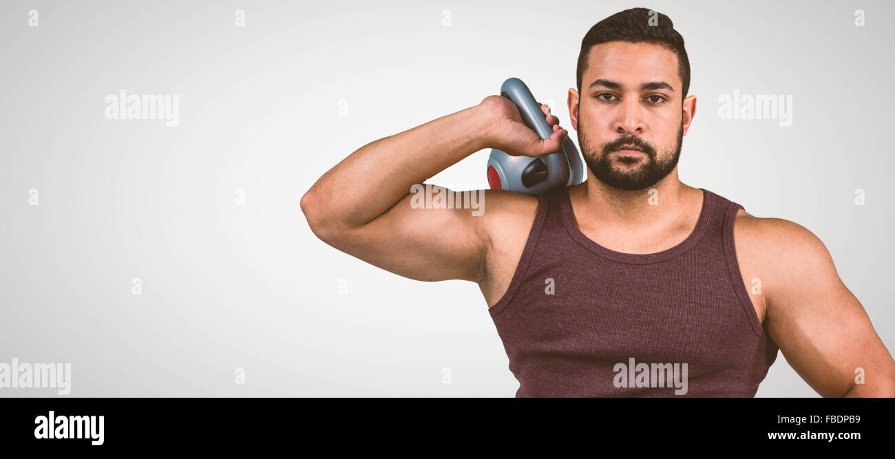 Composite image of muscular serious man holding a kettlebell Stock Photo