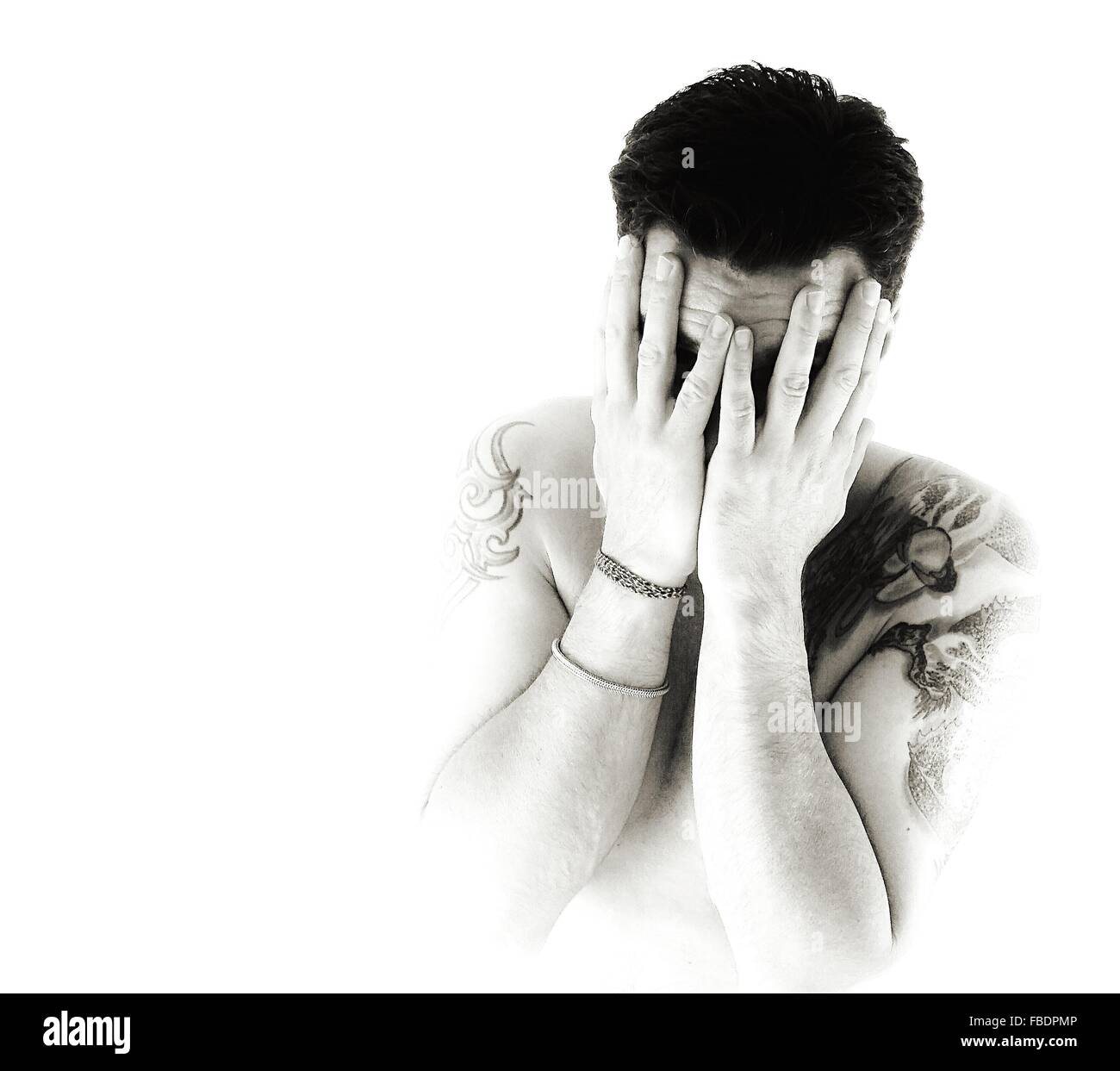 Man With Tattoo Covering Face Against White Background Stock Photo