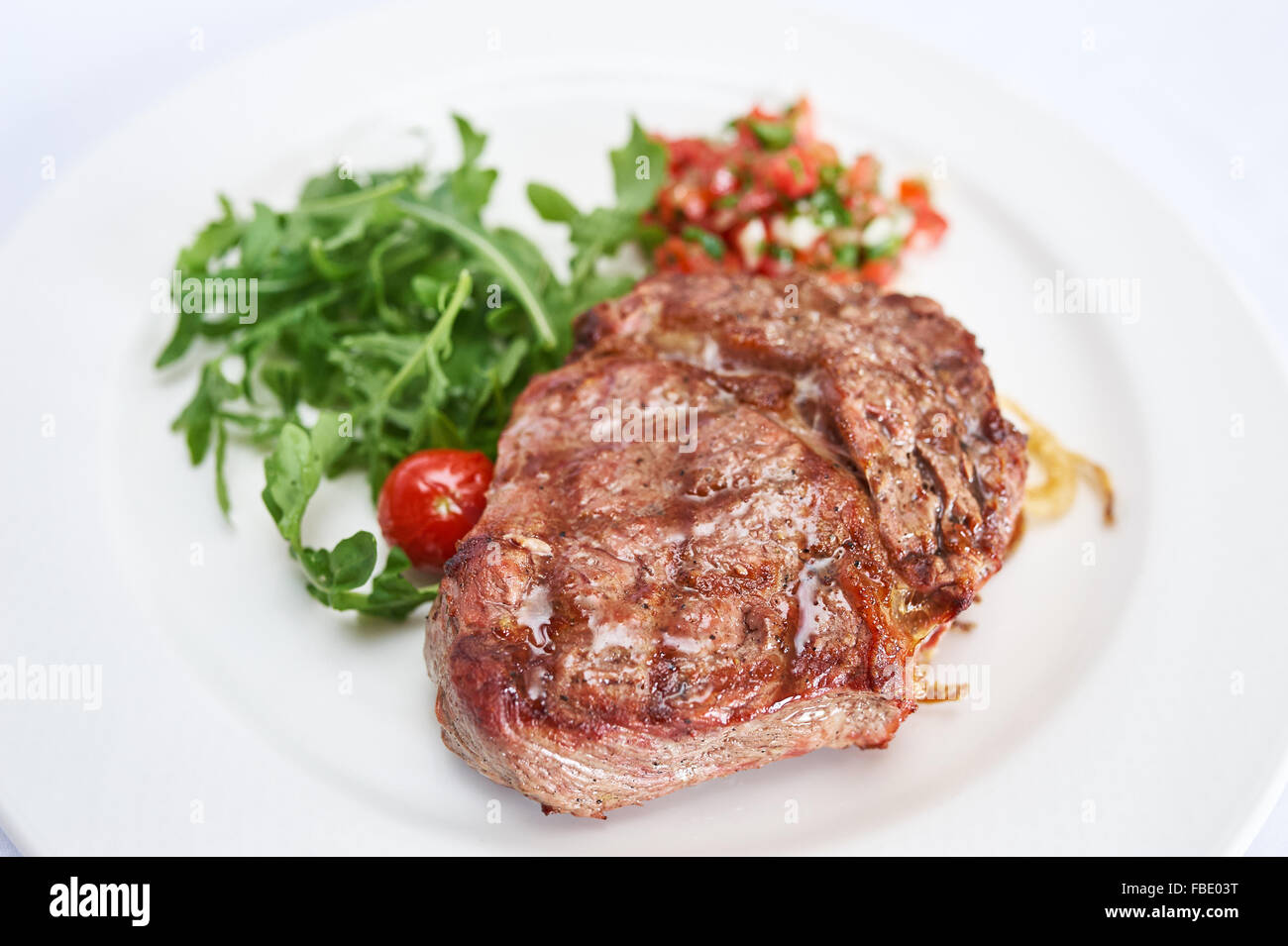 Sirloin steak with tomato tartare on white plate studio shot Stock Photo
