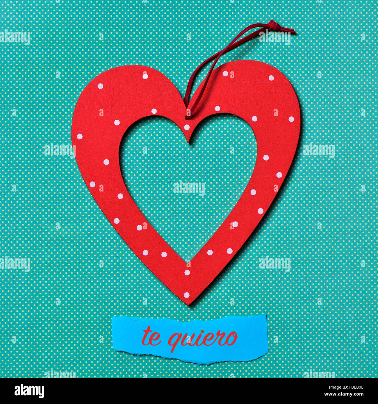 a heart-shaped ornament and the text te quiero, I love you in Spanish, on a colorful blue dot-patterned background Stock Photo