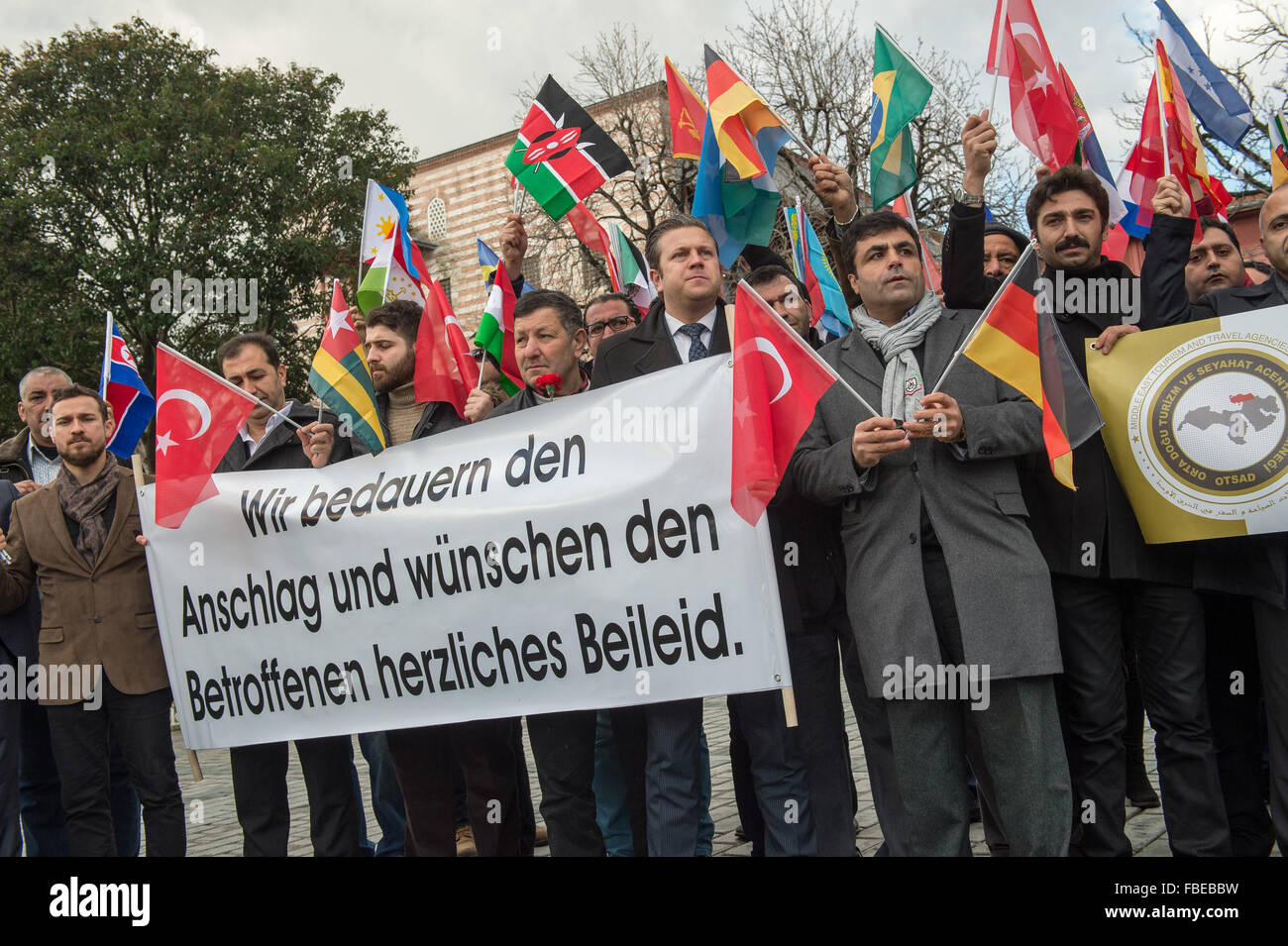 Members of the tourismassociation with international flags and a banner with a German sentence reading «We bemoan the attack and express our condolences to the relatives.» («Wir bedauern den Anschlag und wünschen den Angehörigen herzliches Beileid») at the site of a suicide bombing in the Sultanahmet district of central Istanbul, Turkey, early January 14, 2016. A suicide bombing there on January 12 killed ten German tourists and wounded several others. Photo: Peter Kneffel/dpa Stock Photo
