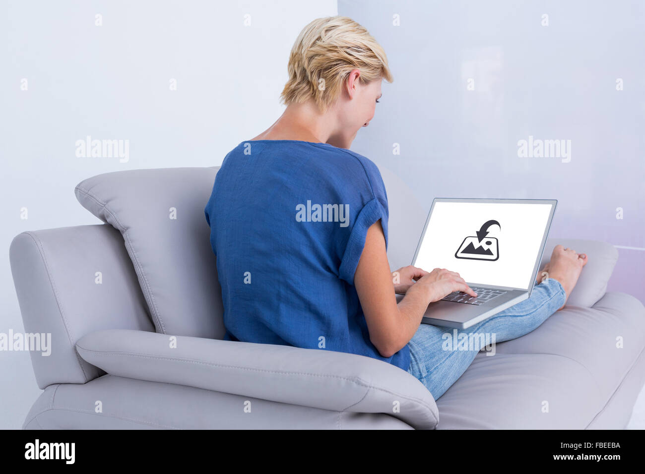 Composite image of blonde woman using her laptop on the couch Stock Photo