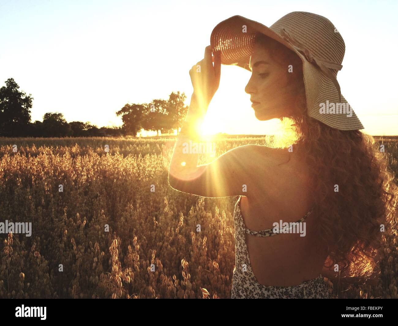 Beautiful Woman Standing On Field Against Clear Sky During Sunset Stock Photo