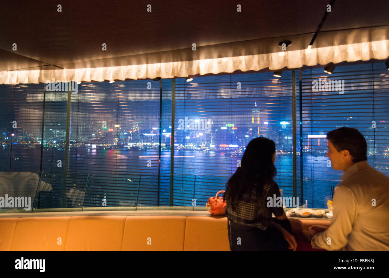 Hong Kong China Peninsula Hotel Felix Bar at night couple at window exclusive expensive with glass and city harbour at night at  Stock Photo