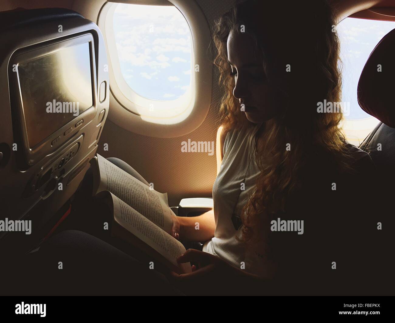 Beautiful Woman Reading Book In Airplane Stock Photo