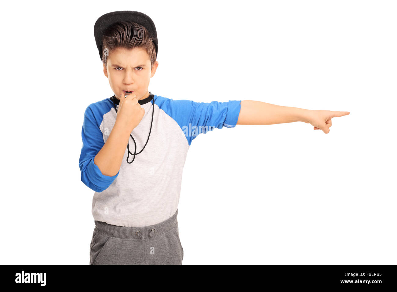 Studio shot of an angry kid in sportswear blowing a whistle and pointing right isolated on white background Stock Photo