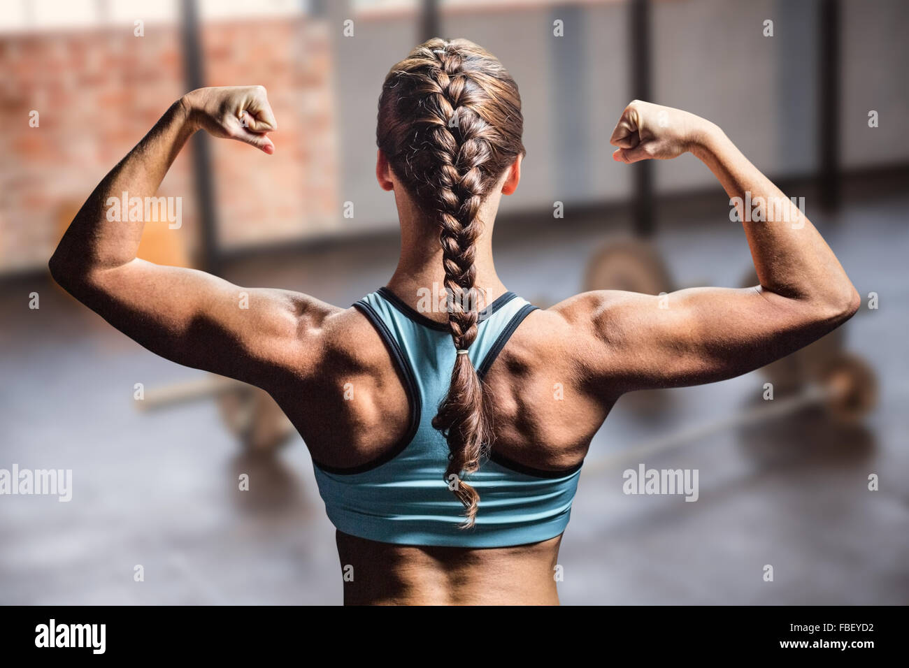 Composite image of rear view of woman with braided hair flexing muscles Stock Photo