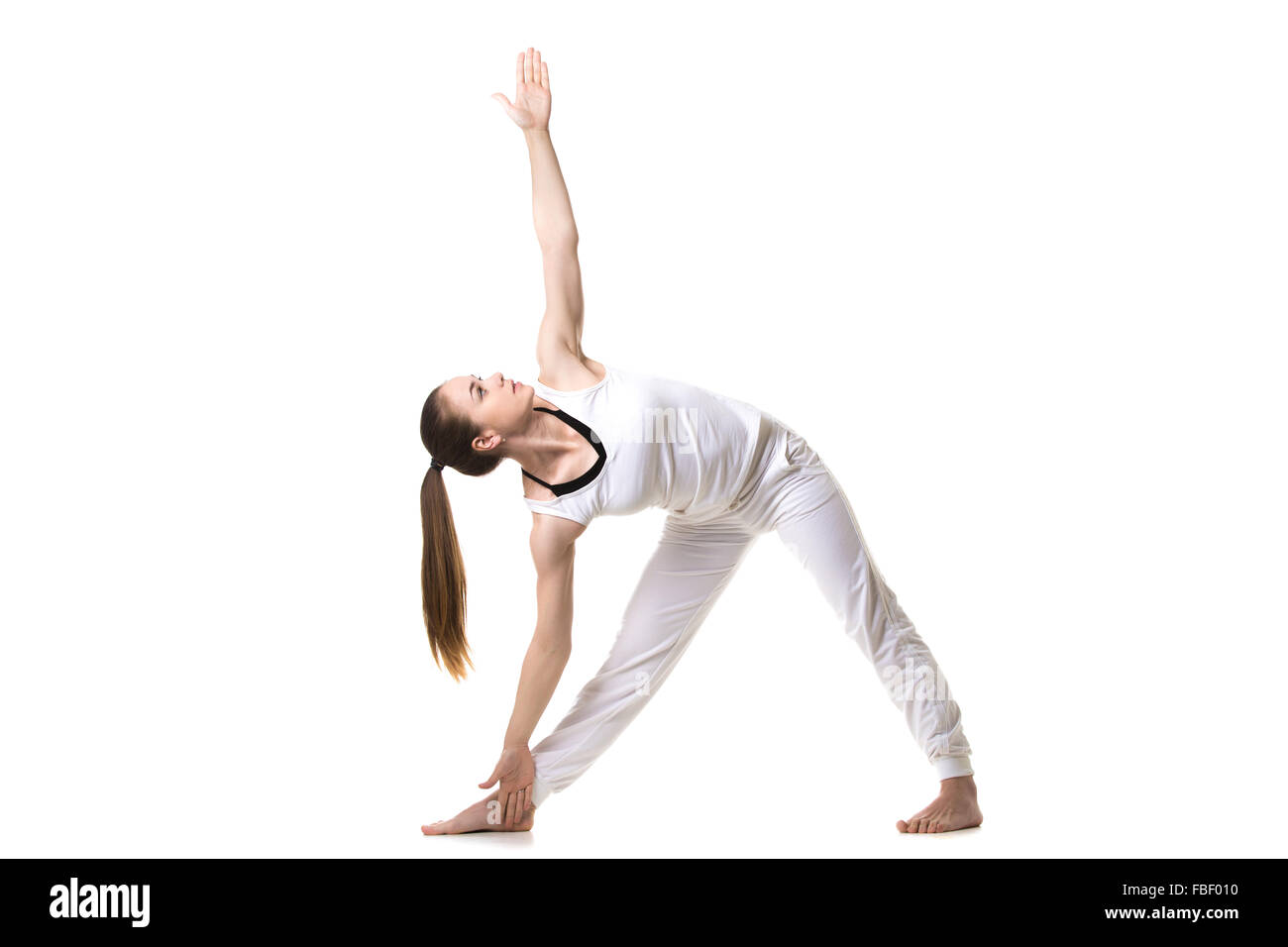 Beautiful fitness model practices yoga or pilates, standing in Triangle yoga pose, Trikonasana, stretching exercise, front view Stock Photo