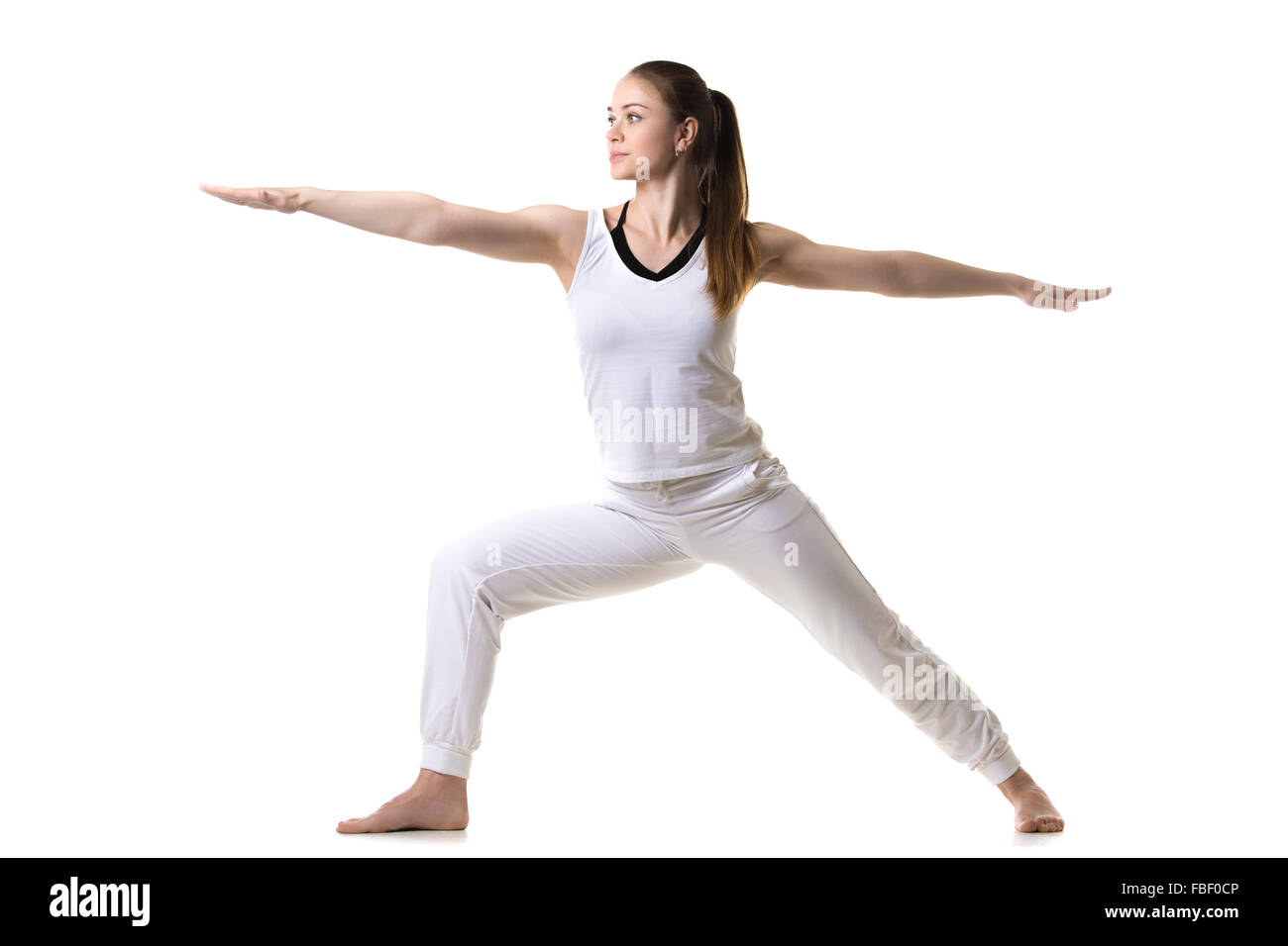 Beautiful fitness model practices yoga or pilates, doing lunge exercise, standing in Warrior II posture, Virabhadrasana 2, side Stock Photo