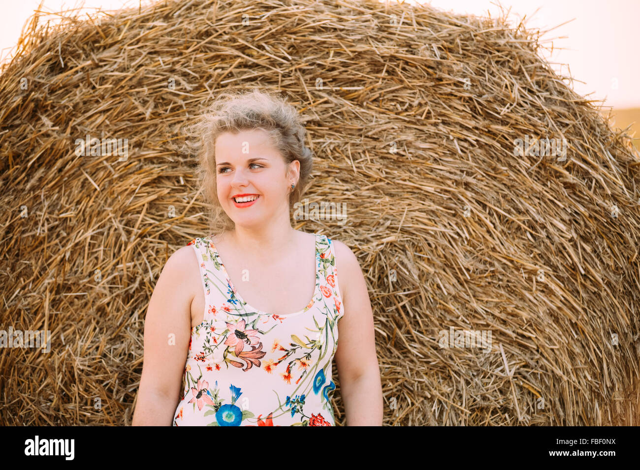 Beautiful Plus Size Young Woman In Shirt Posing In Summer Field Meadow Near Hay Bales At Sunset Background Stock Photo