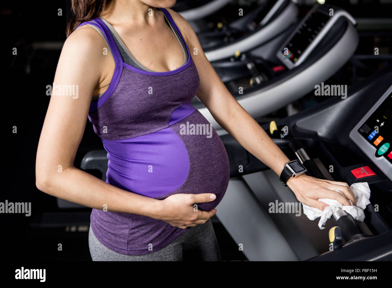 Pregnant woman touching belly on treadmill Stock Photo Alamy