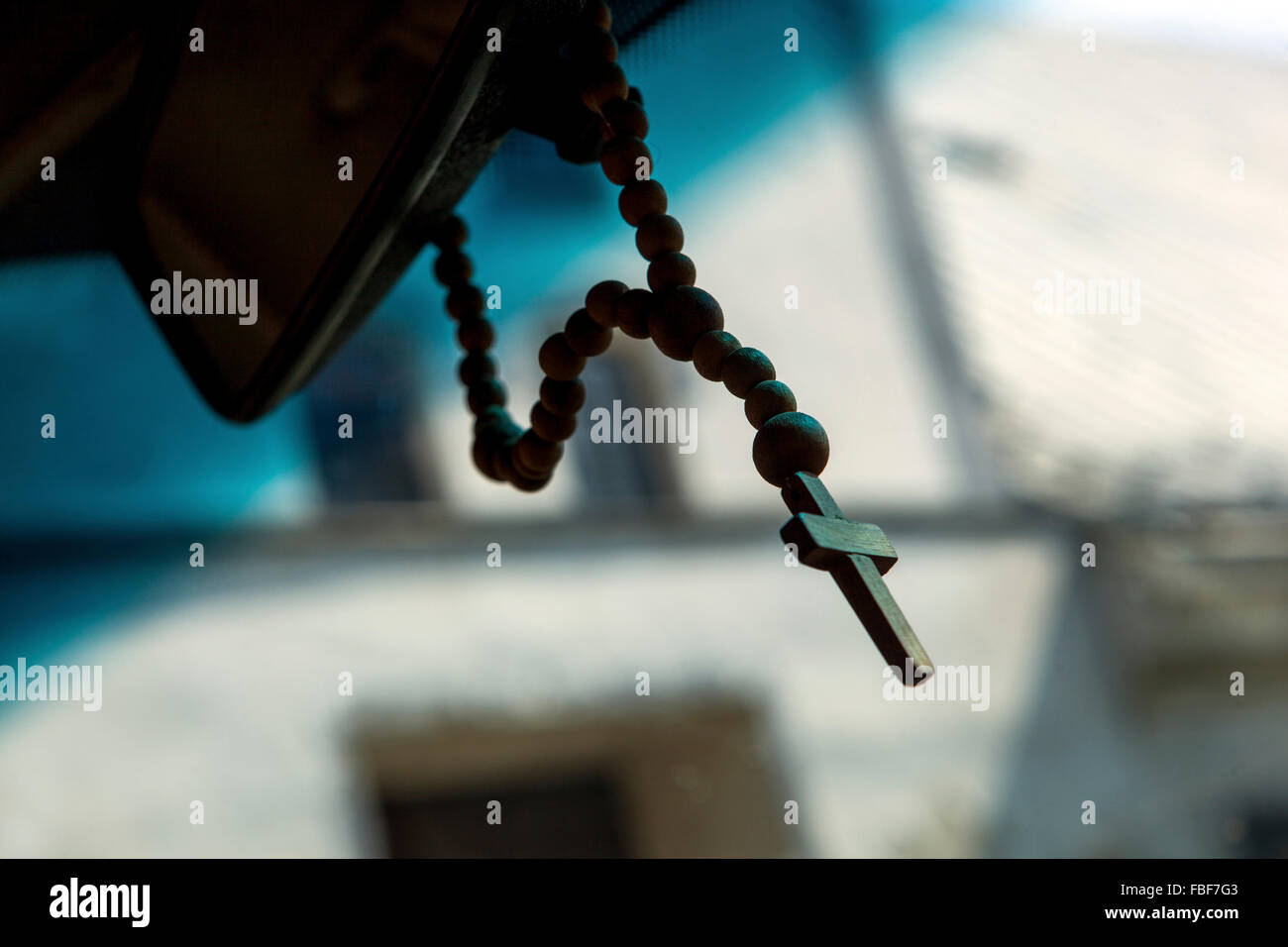 Rosary hanging from rear view mirror in car Stock Photo