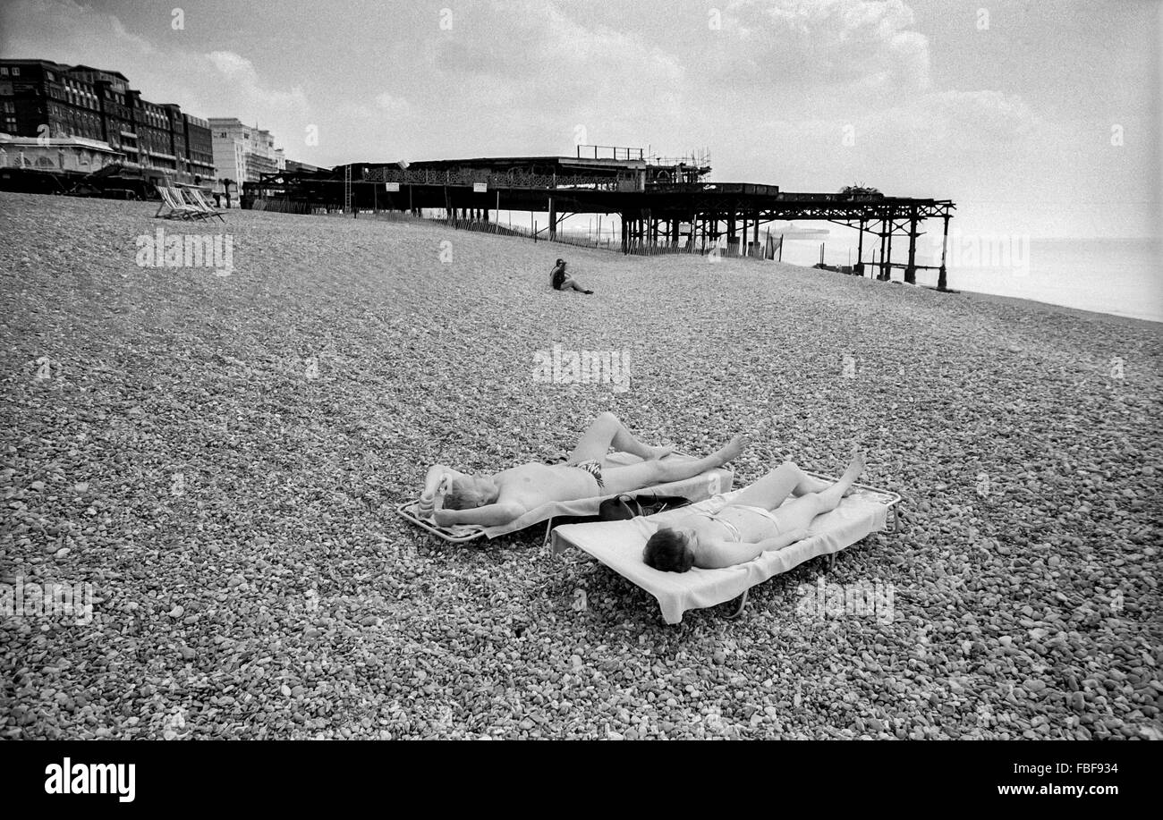 Sunbathers on Brighton beach near the derelict West Pier in 1989 Stock Photo
