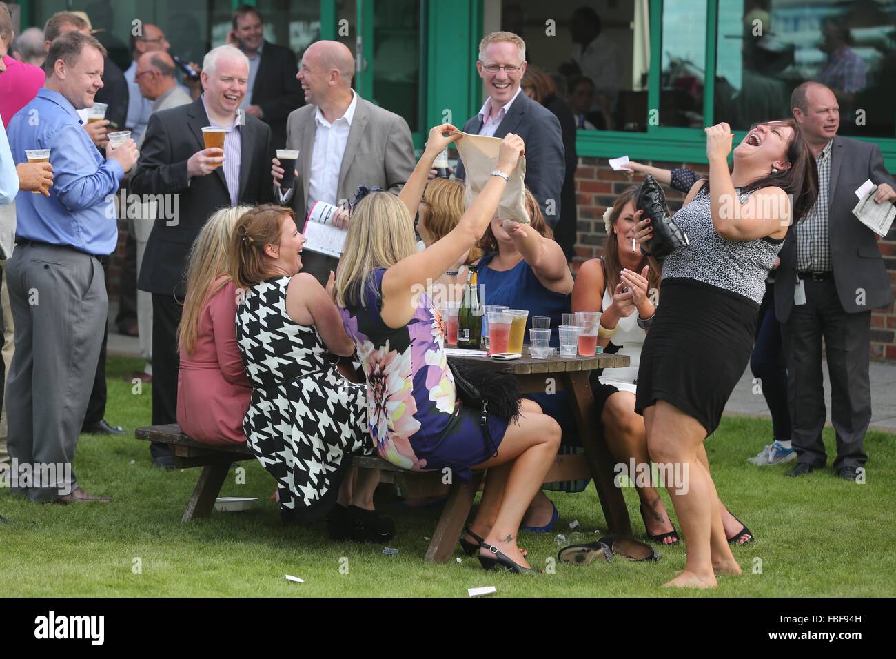 Brighton Race Course Ladies Day. Ladies sitting drinking and laughing whilst waving a pair of knickers as the beer drinking men Stock Photo